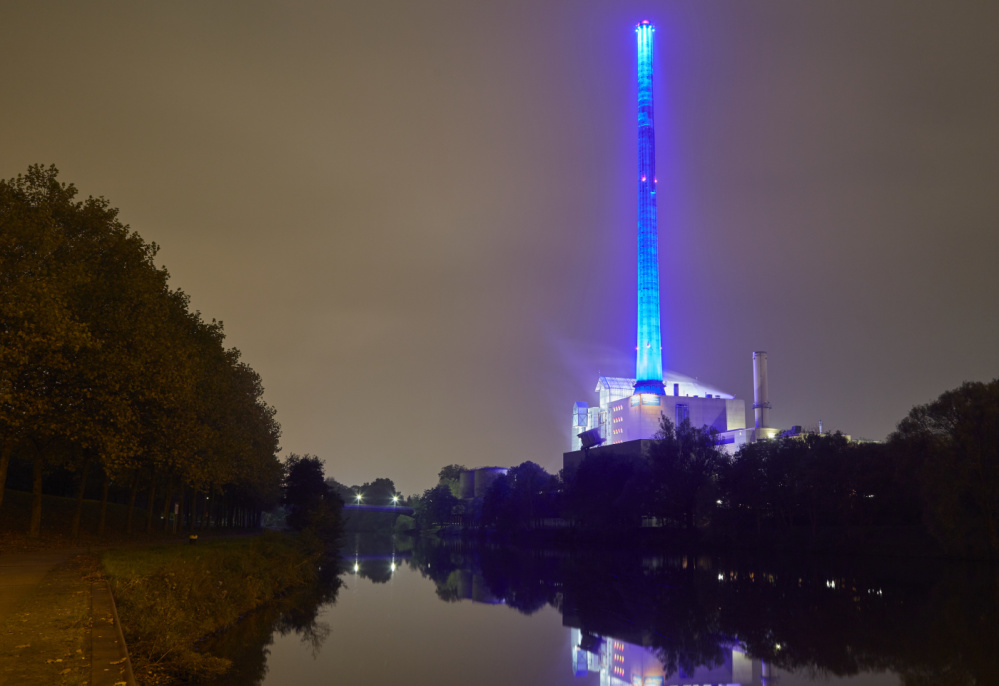 Seit 2014 wird der Schornstein von farbigen LED-Scheinwerfern angestrahlt Heizkraftwerk bei Nacht